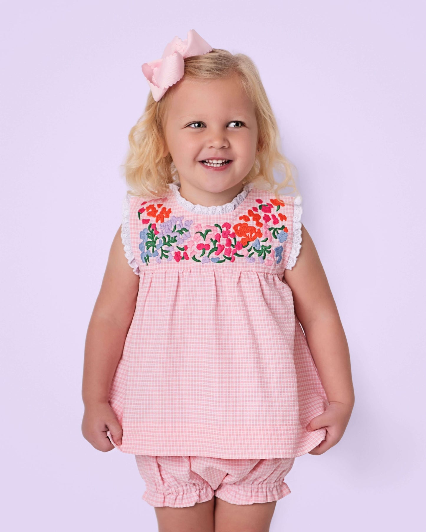Young girl wearing a pink floral dress with a lavender background