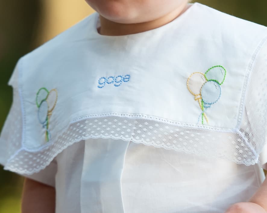 Baby bib with embroidered name and balloons on a white background