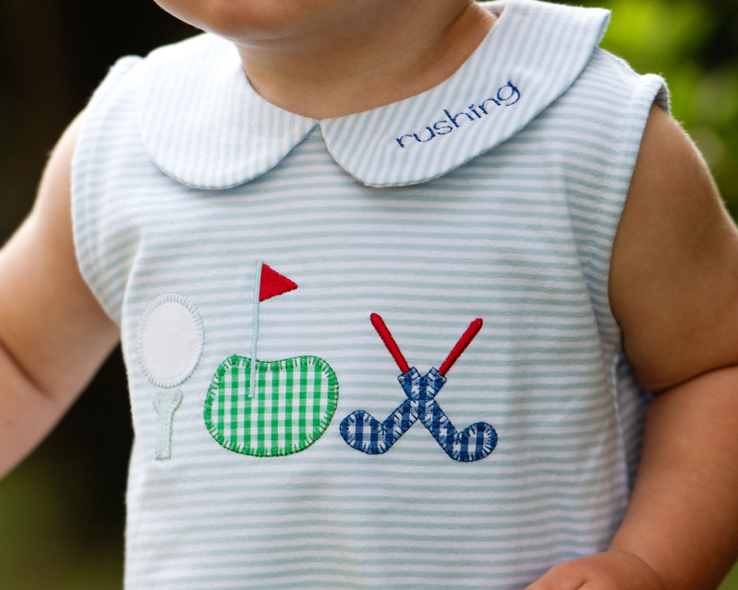 Baby dress with sports-themed appliqués on a blurred background