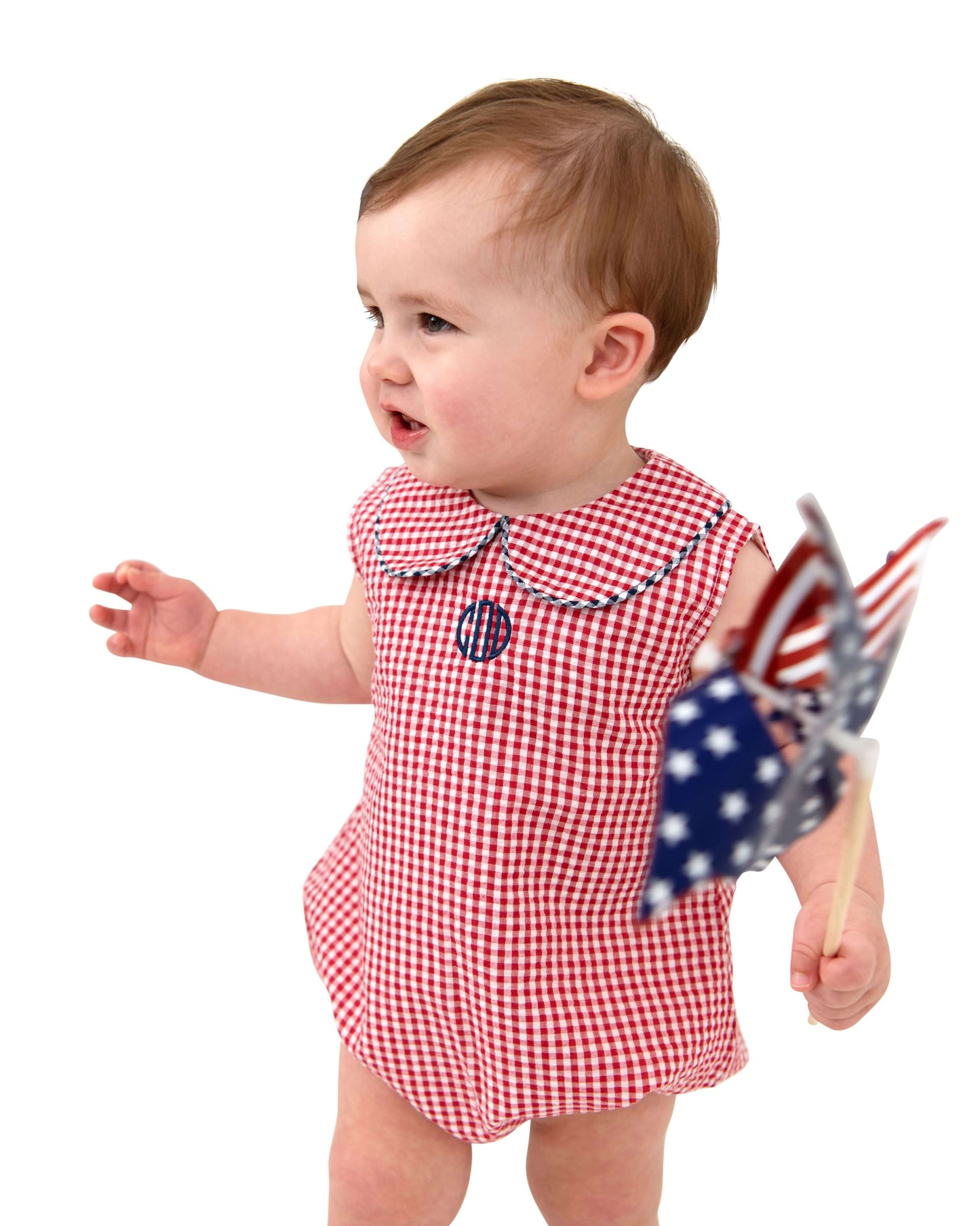 Baby in a red checkered romper with a flag, on a white background