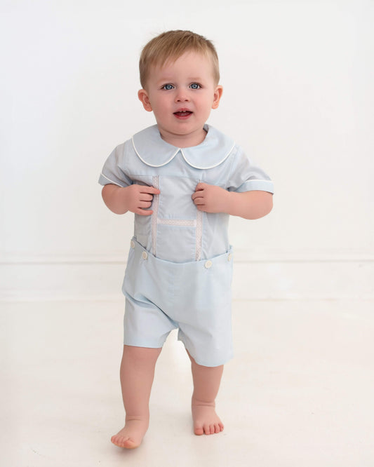 Baby wearing a light blue outfit with a collar on a white background