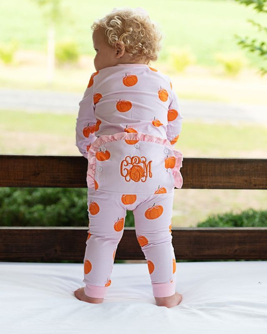 Baby wearing a pink zipper pajama with orange pumpkin.