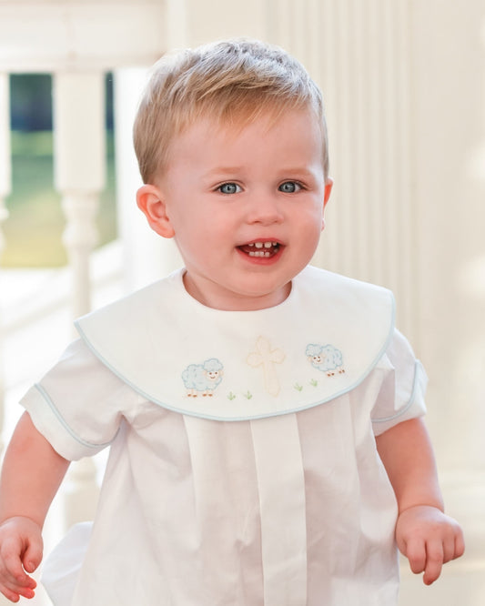 Baby wearing a white outfit with embroidered details on a blurred background