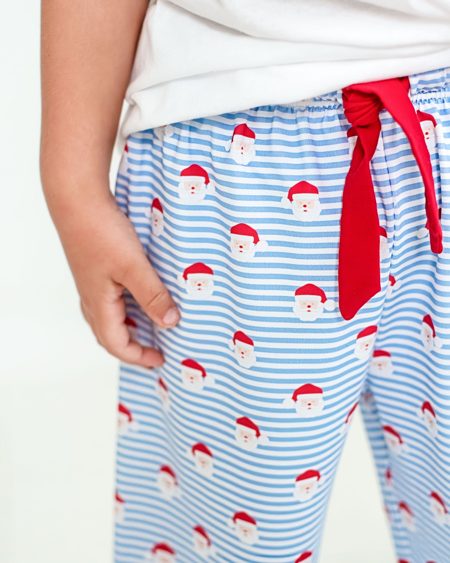 Blue striped pajama pants with Santa Claus pattern and red tie on a white background