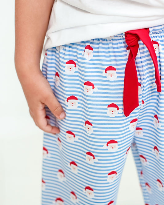 Blue striped pajama pants with Santa Claus pattern and red tie on a white background