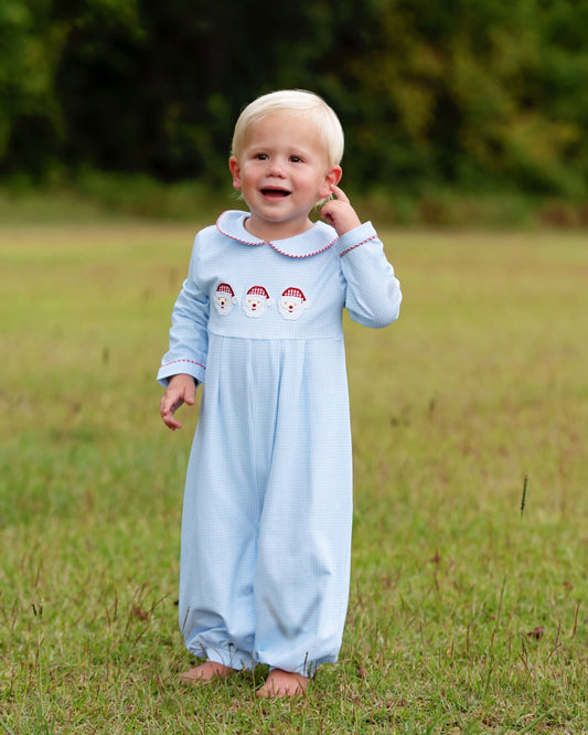 Boy in santa outfit standing in a grassy field
