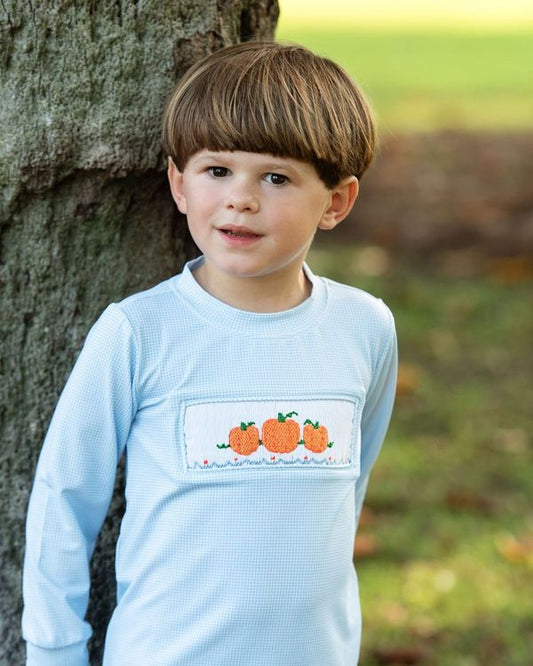 Boy wearing a light blue shirt with a pumpkin design outdoors