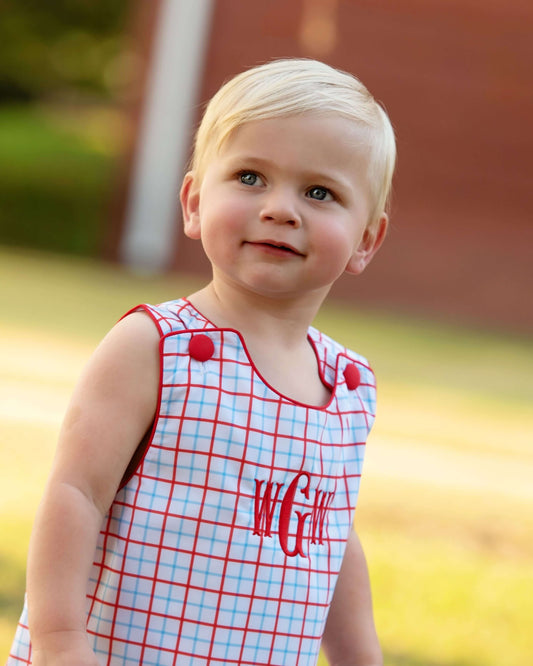 Boy wearing a windowpane outfit with red buttons and a monogram on the chest.