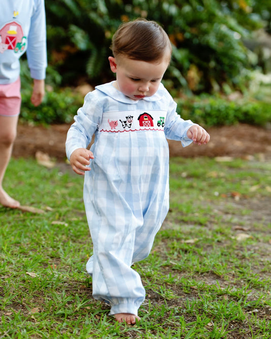 Child in a checkered outfit with farm-themed design walking outdoors.