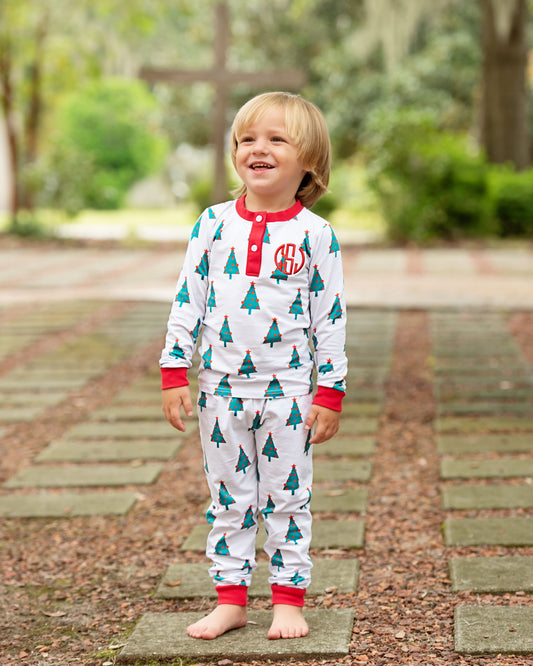 Child wearing Christmas-themed pajamas standing on a stone path outdoors.
