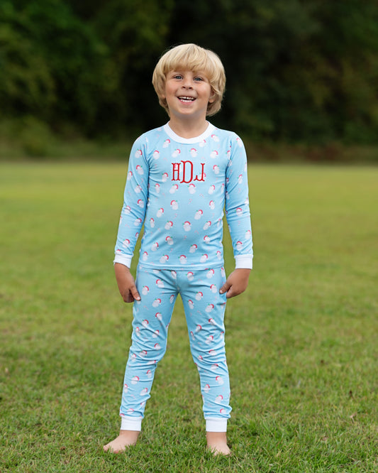 Child wearing a light blue pajama set with red letters outdoors on grass