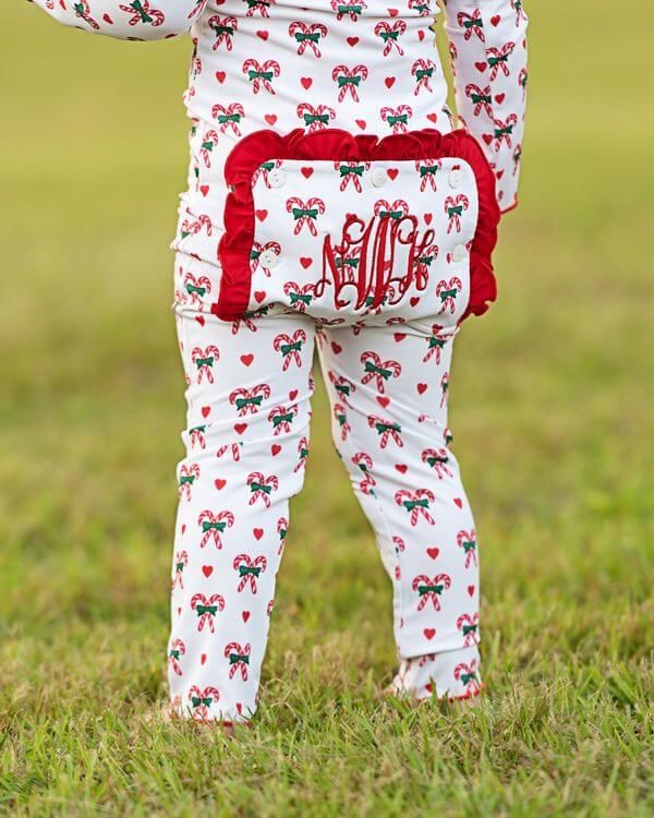 Child wearing a Christmas-themed outfit with red and green patterns on grass
