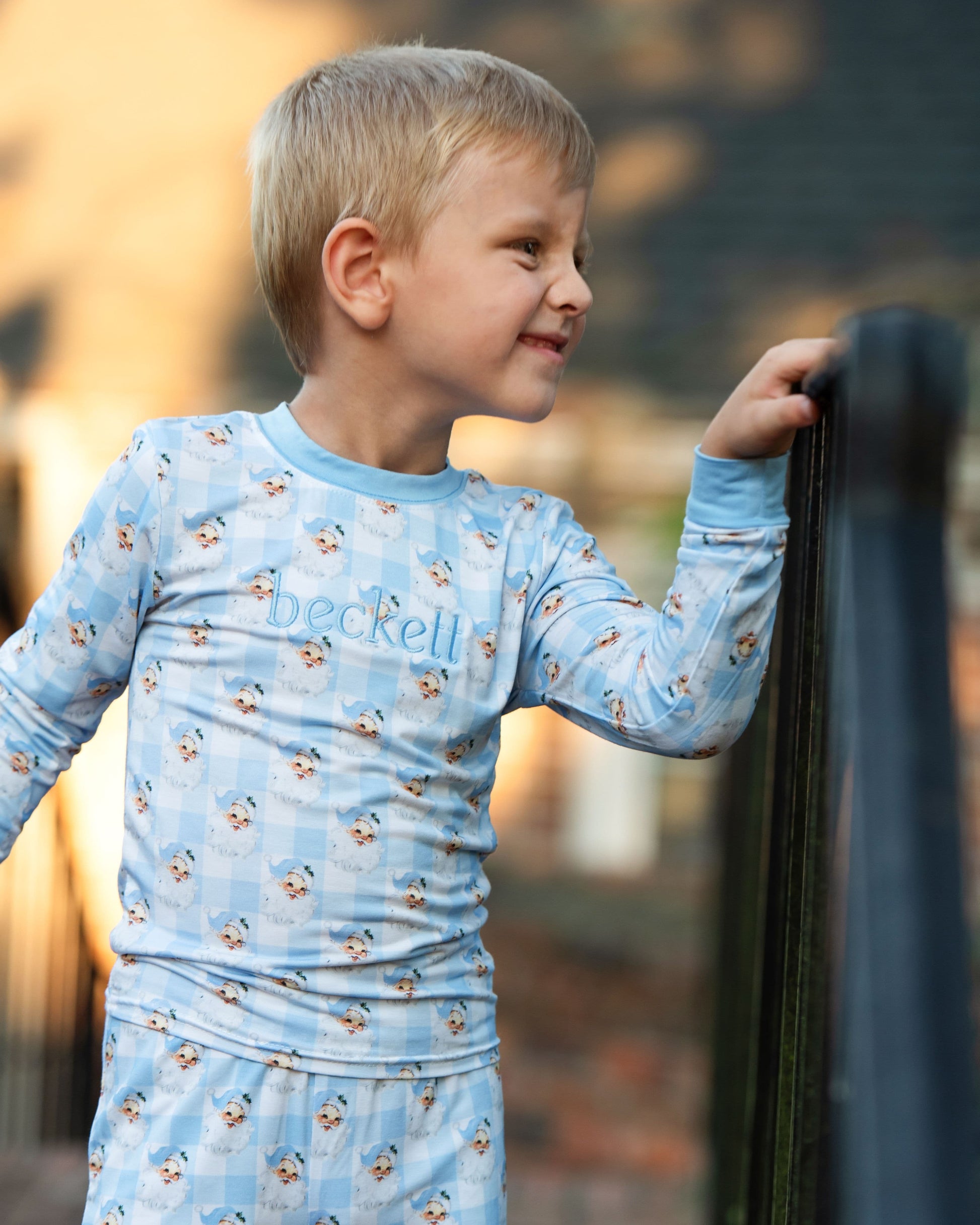 Child wearing a blue long-sleeve shirt with 'beckell' branding outdoors.