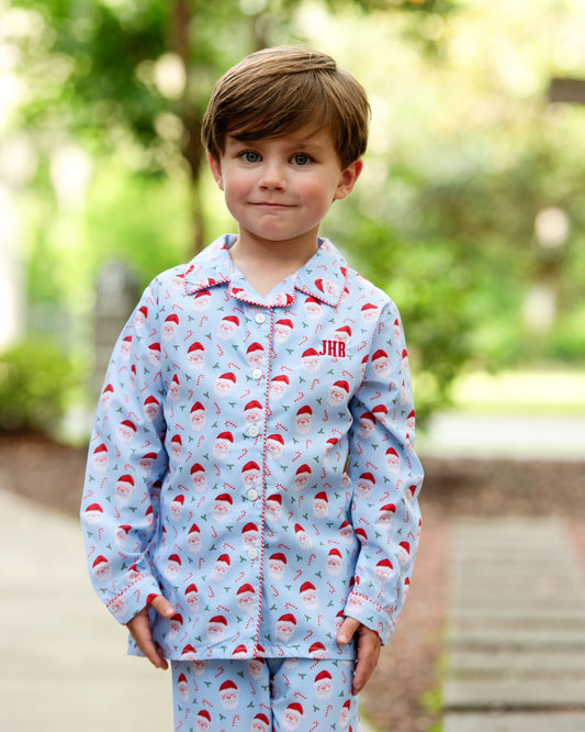 Child wearing a blue pajama set with Santa hats outdoors