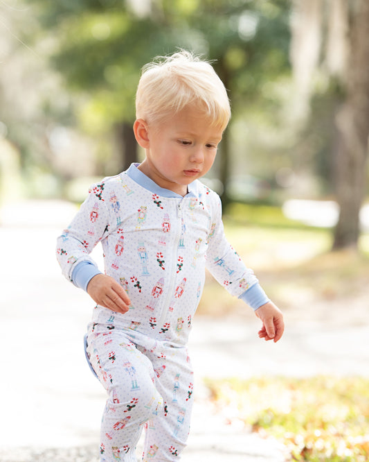 Child wearing a floral onesie outdoors with trees and grass in the background