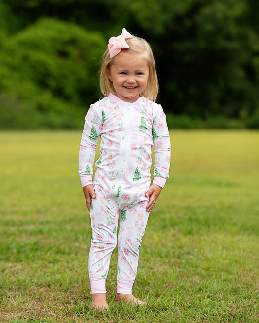 Child wearing a floral onesie standing in a grassy field
