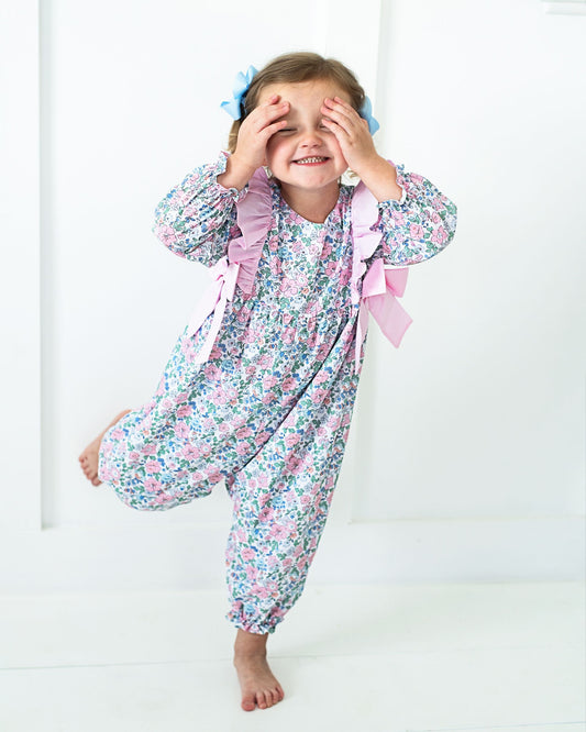 Child wearing a floral pajama set with ruffles on a white background