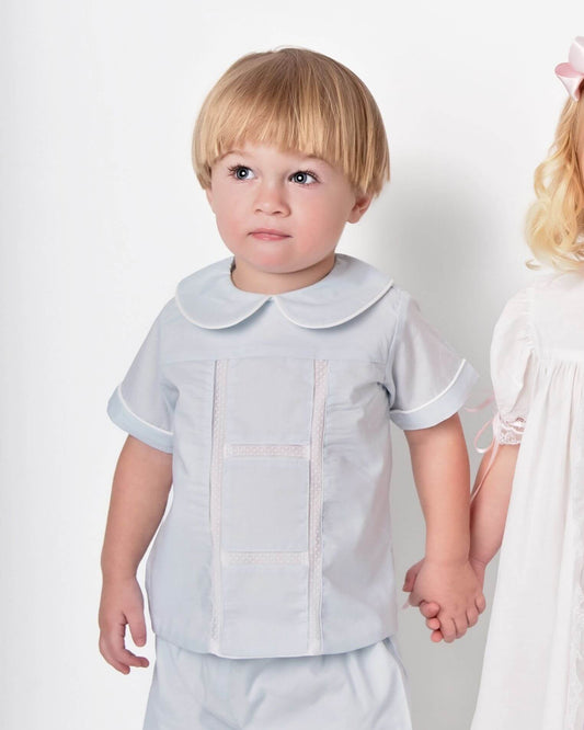 Child wearing a light blue outfit with a white collar against a plain background