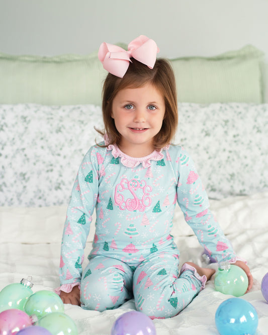 Child wearing a light blue pajama set with pink accents, sitting on a bed with colorful balloons.