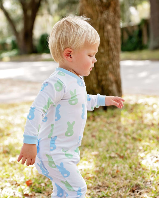 Child wearing a light blue pajama with colorful animal prints outdoors.