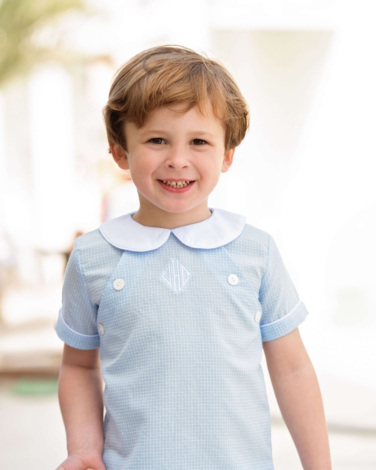 Child wearing a light blue short set with a white collar outdoors