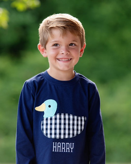 Child wearing a navy blue sweatshirt with a duck design and 'HARRY' text, standing outdoors.