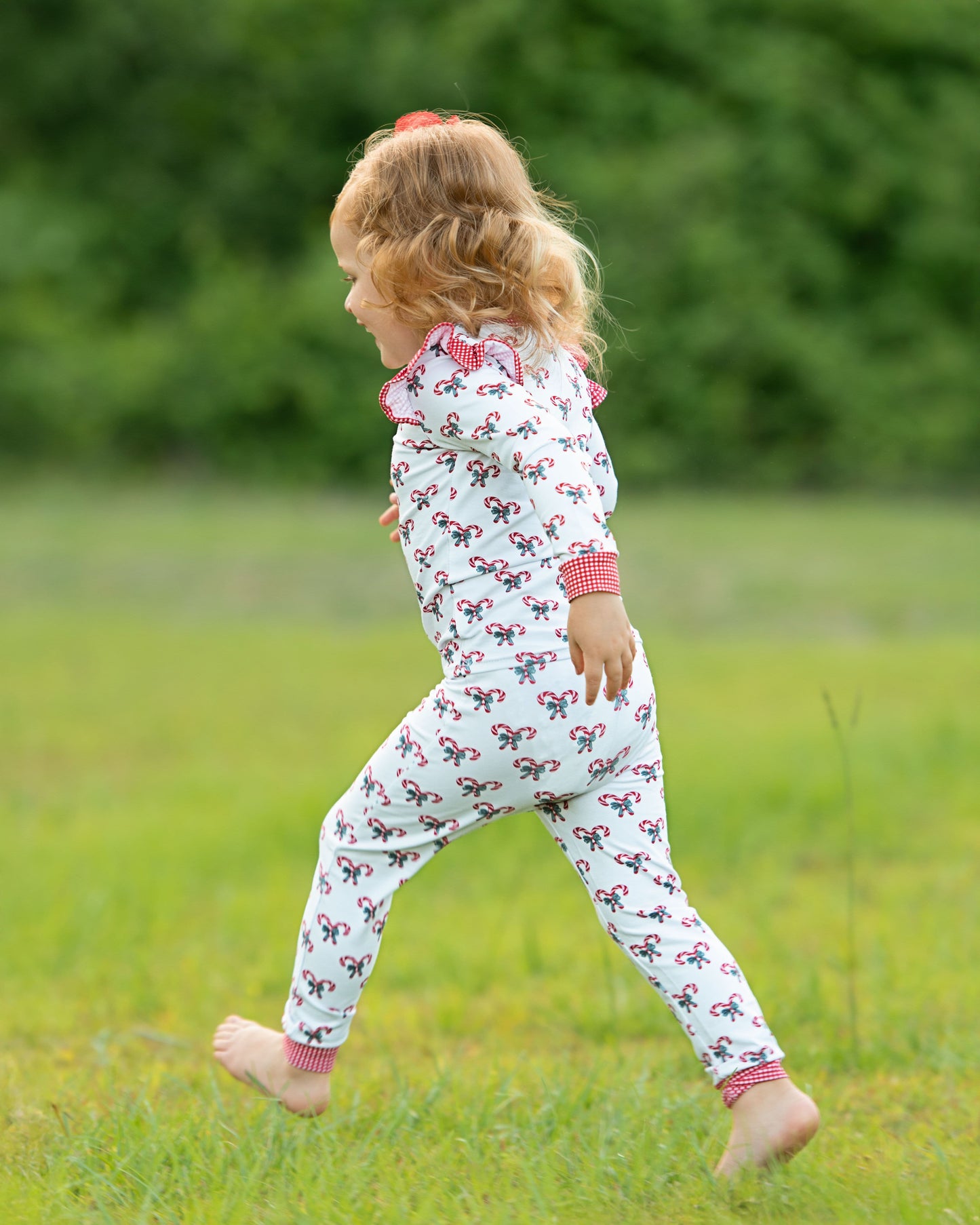 Child wearing a patterned outfit with pink trim in a grassy field