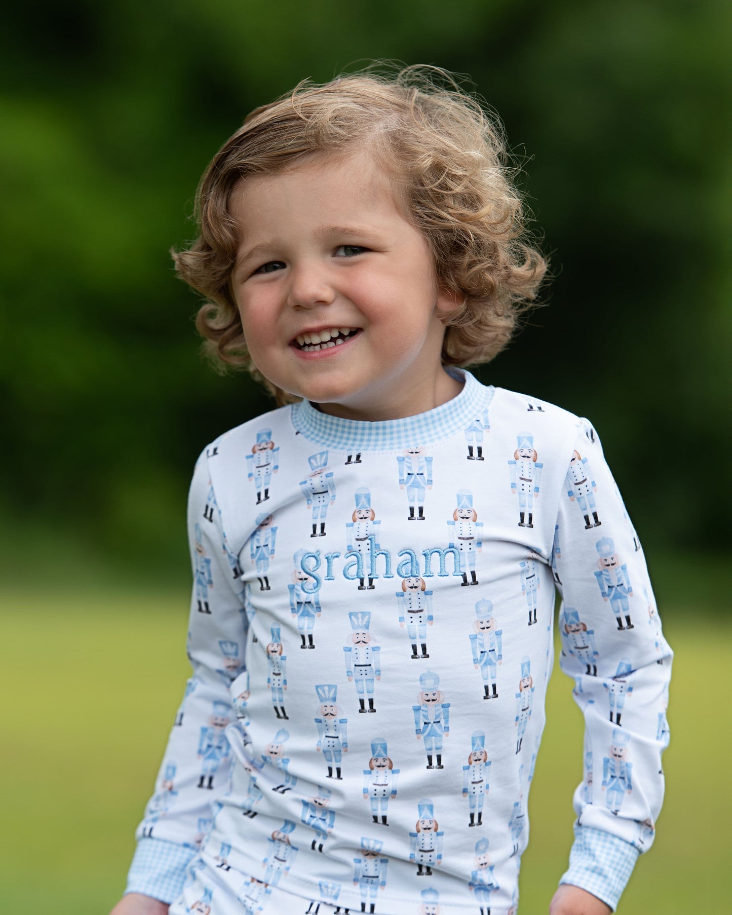 Child wearing a patterned shirt with 'graham' printed on it, standing outdoors.
