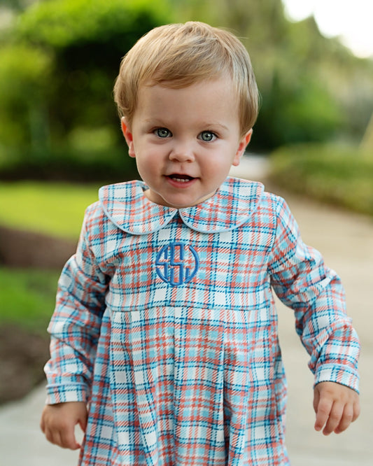 Child wearing a plaid dress with a monogram outdoors