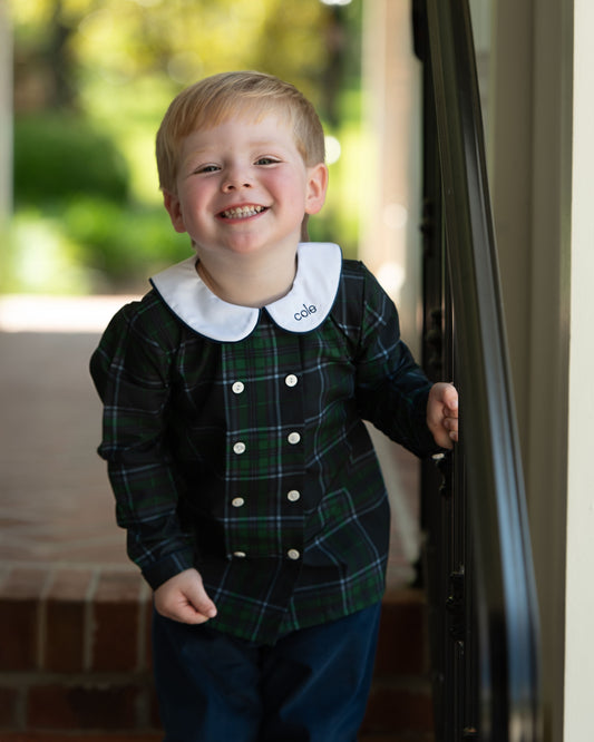 Child wearing a plaid dress with a white collar indoors
