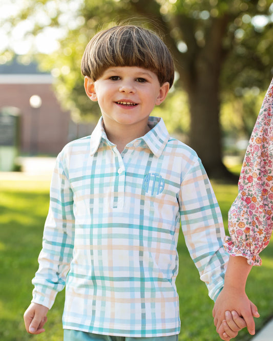 Child wearing a plaid shirt standing outdoors with a blurred background
