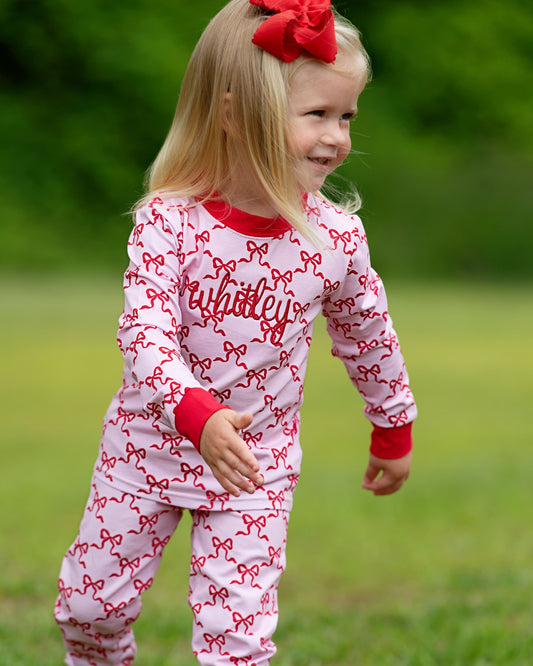 Child wearing a red and white outfit with bows outdoors