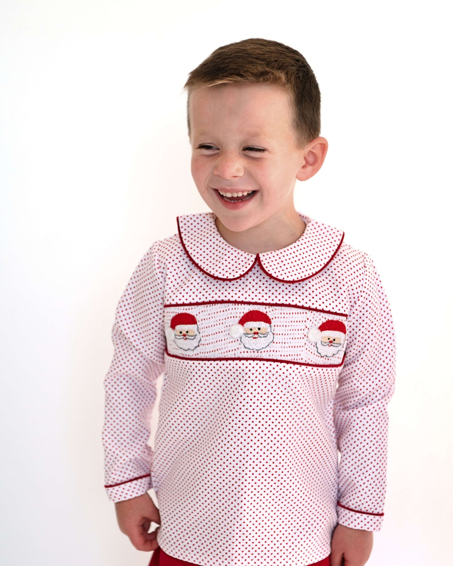 Child wearing a red and white patterned dress with embroidered details on a white background