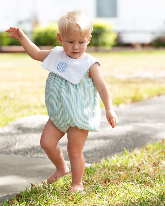 Child wearing a striped romper with a bib outdoors