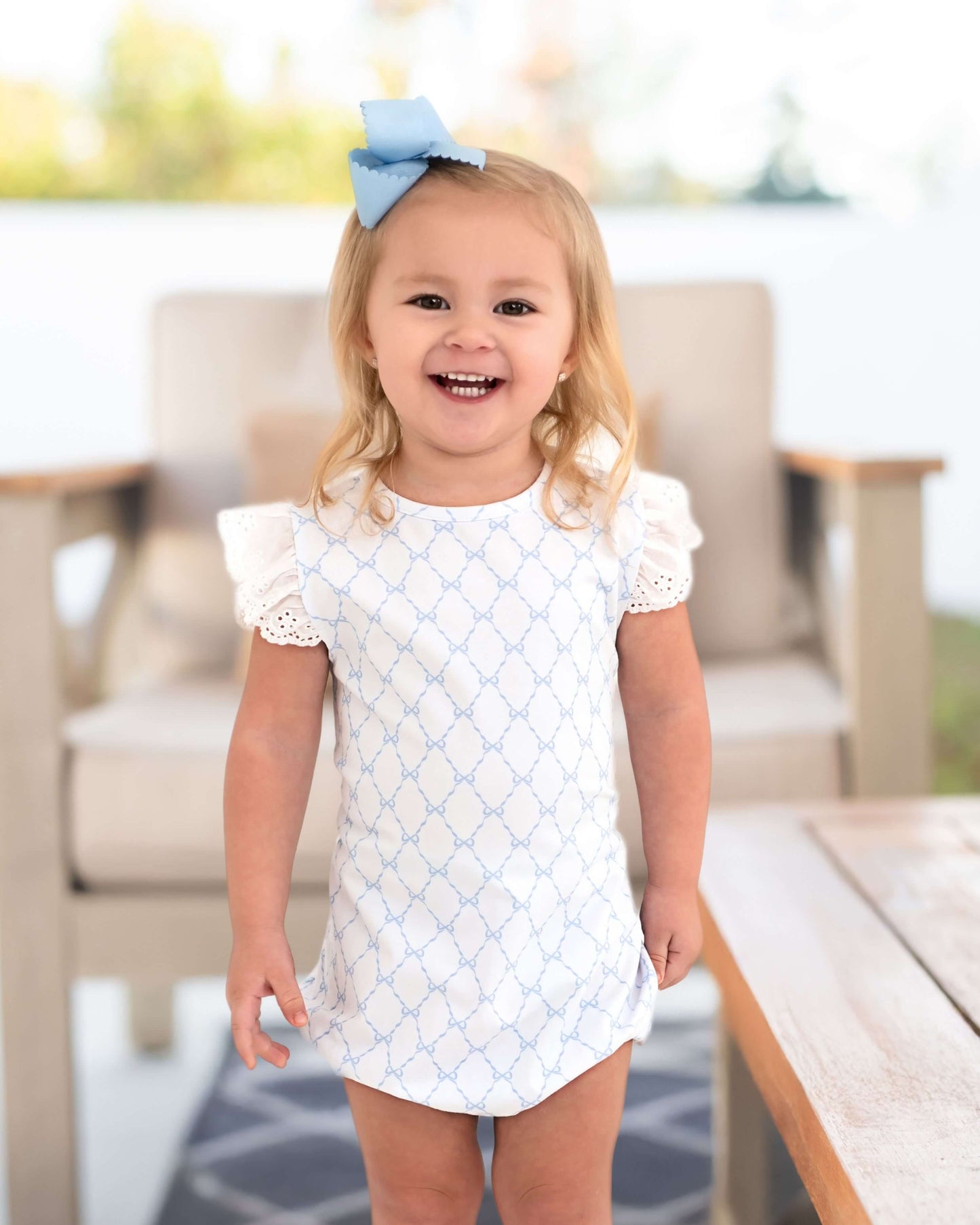 Child wearing a white dress with blue patterns outdoors