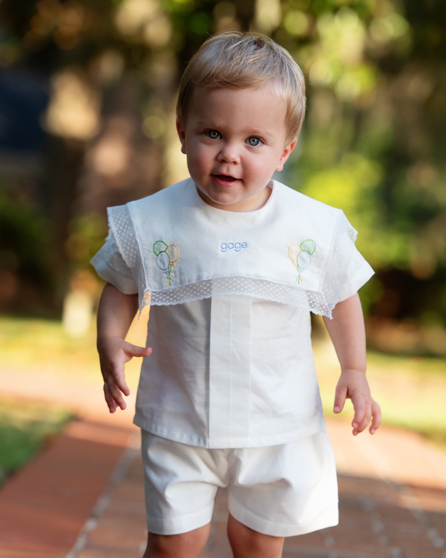 Child wearing a white outfit with lace details outdoors