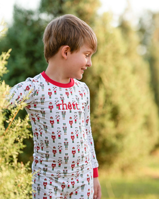 Child wearing pajamas with a Christmas nutcracker pattern outdoors.