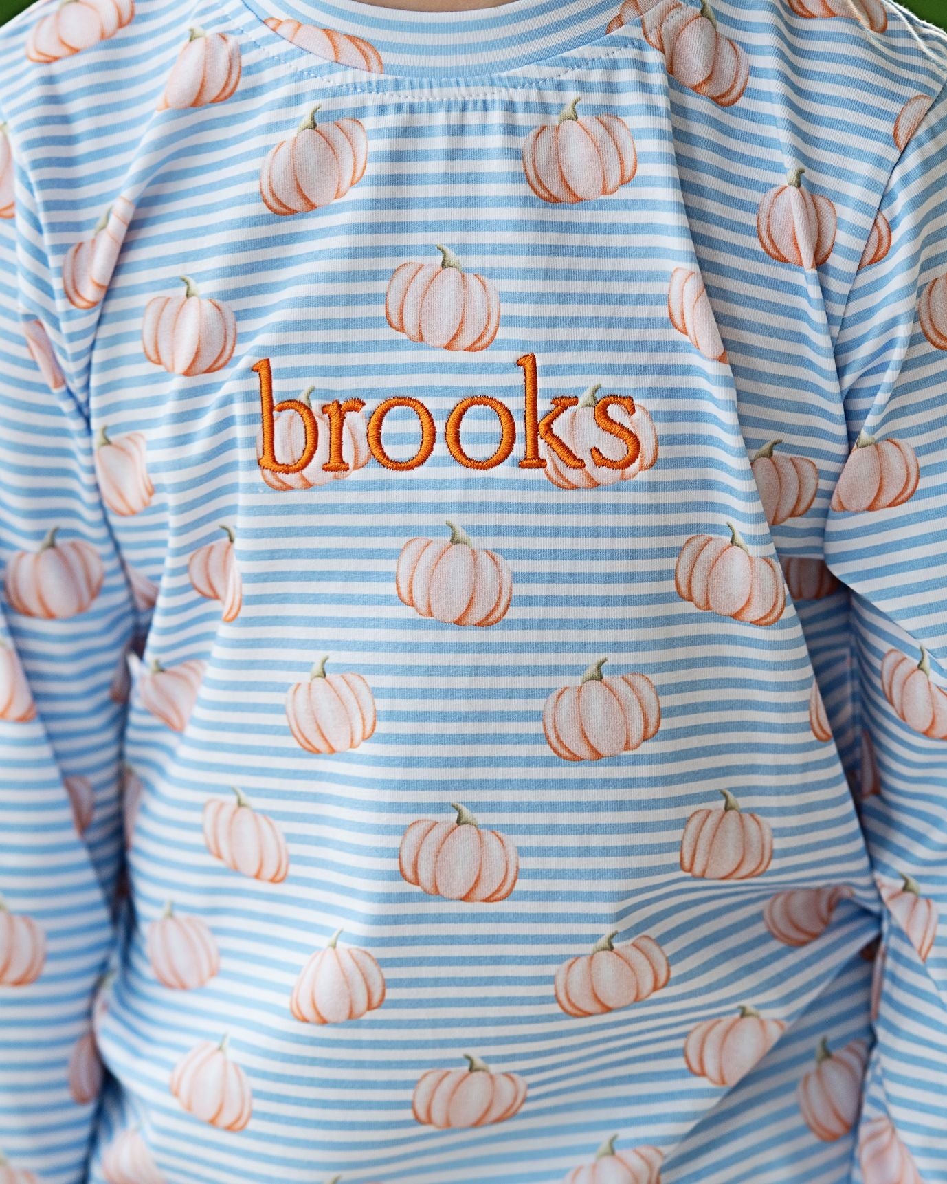 Children's outfit with pumpkin pattern and 'brooks' text on a blue and white striped background