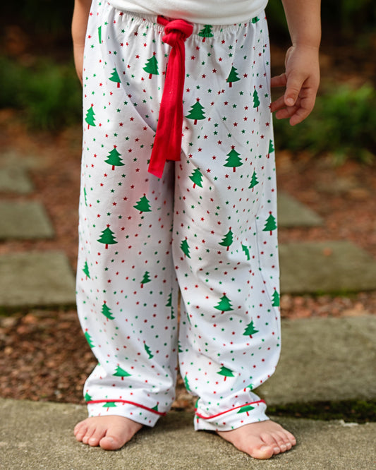 Children's pajama pants with Christmas tree and dot pattern on a blurred outdoor background