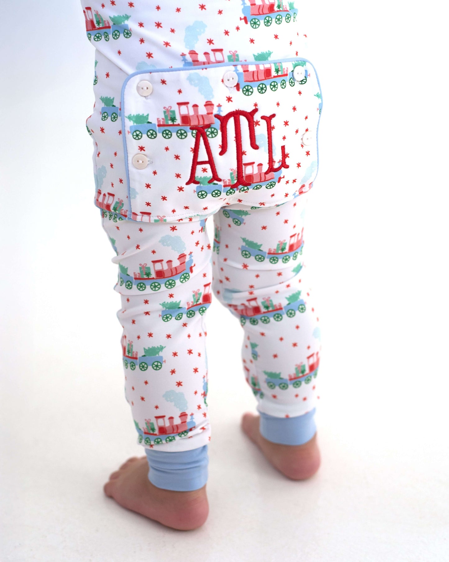 Children's pajama set with train pattern and 'ATL' monogram on a white background