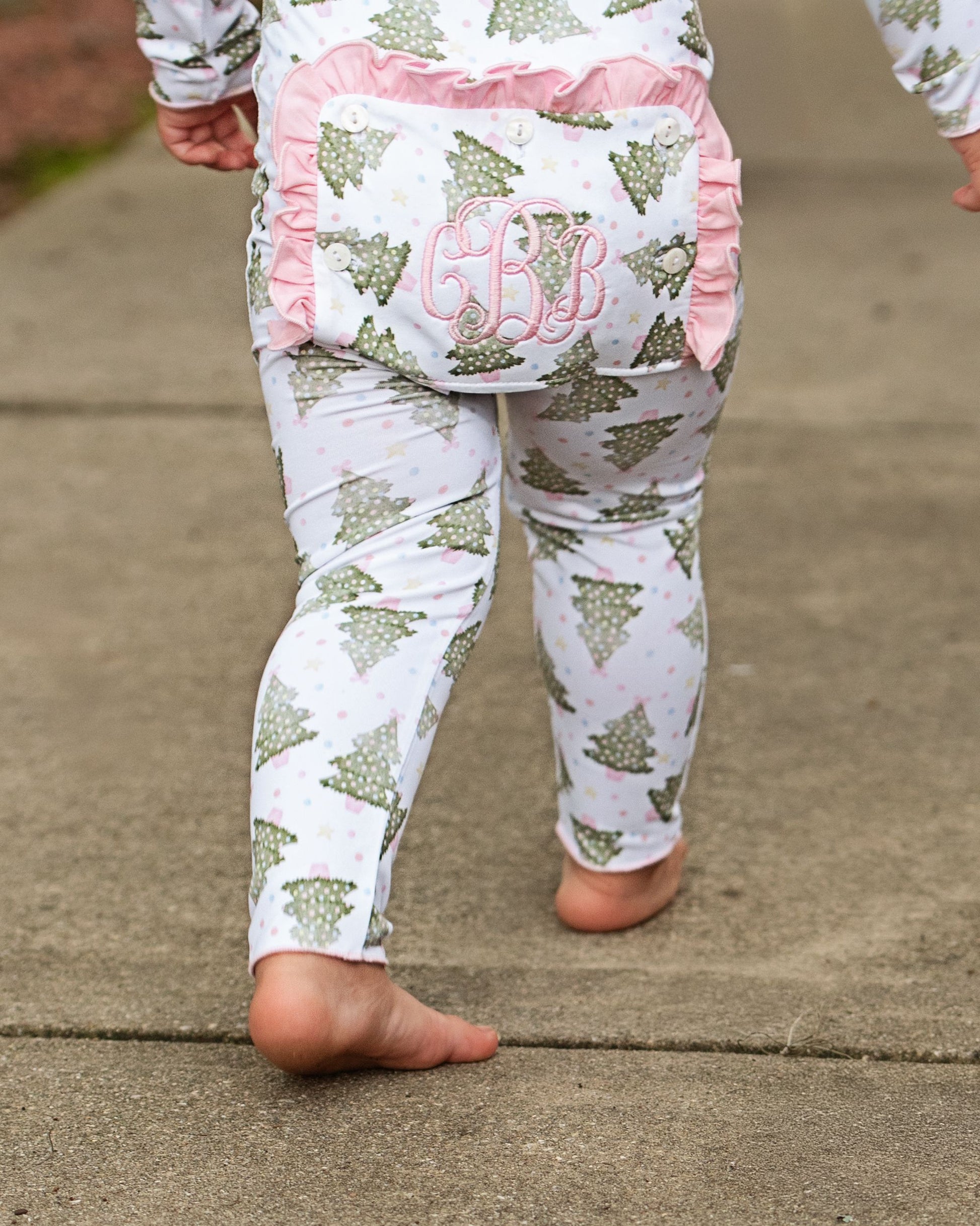 Children's pajama set with tree pattern and pink accents on a concrete surface