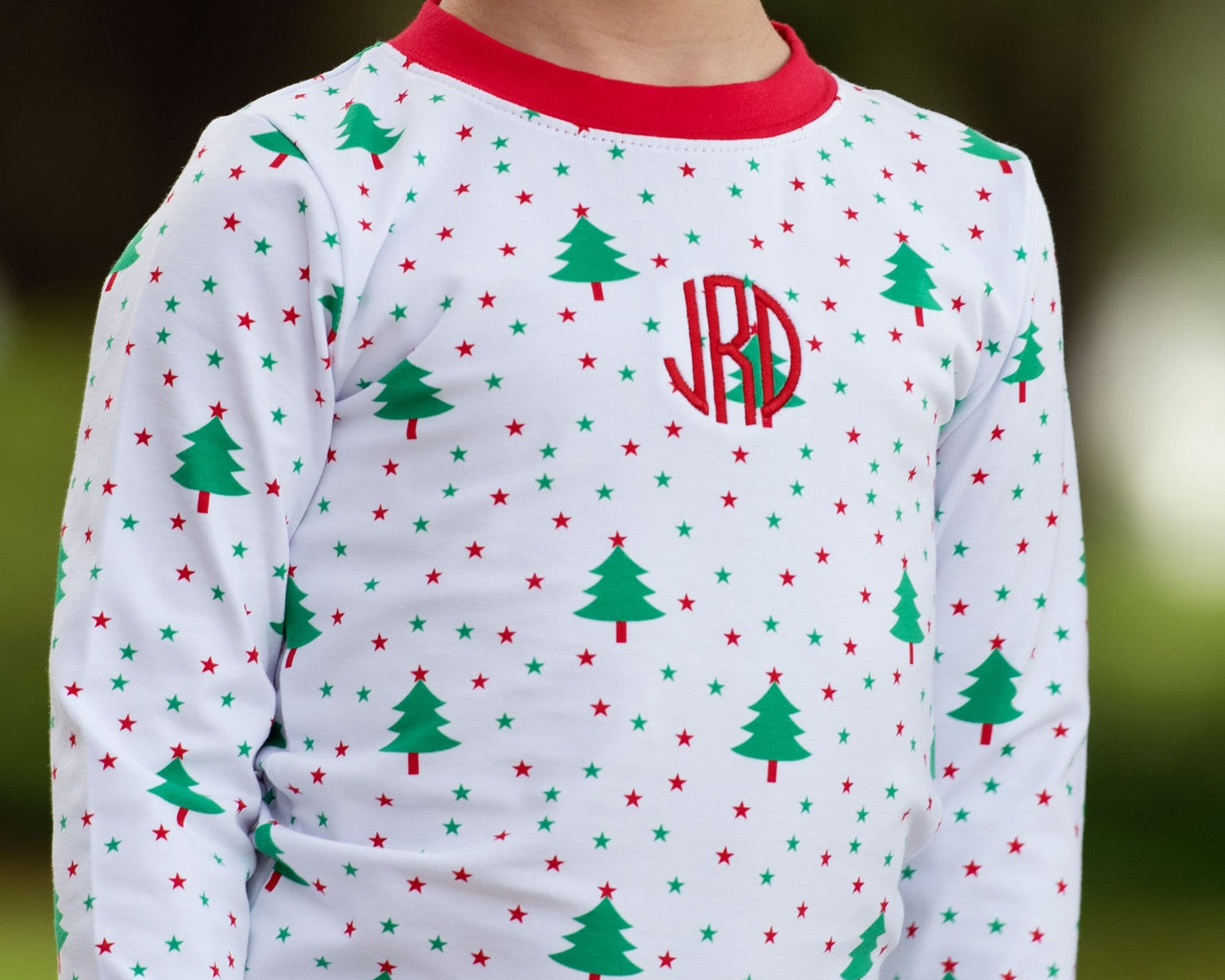 Children's pajama top with Christmas tree and star pattern and monogram on a blurred background
