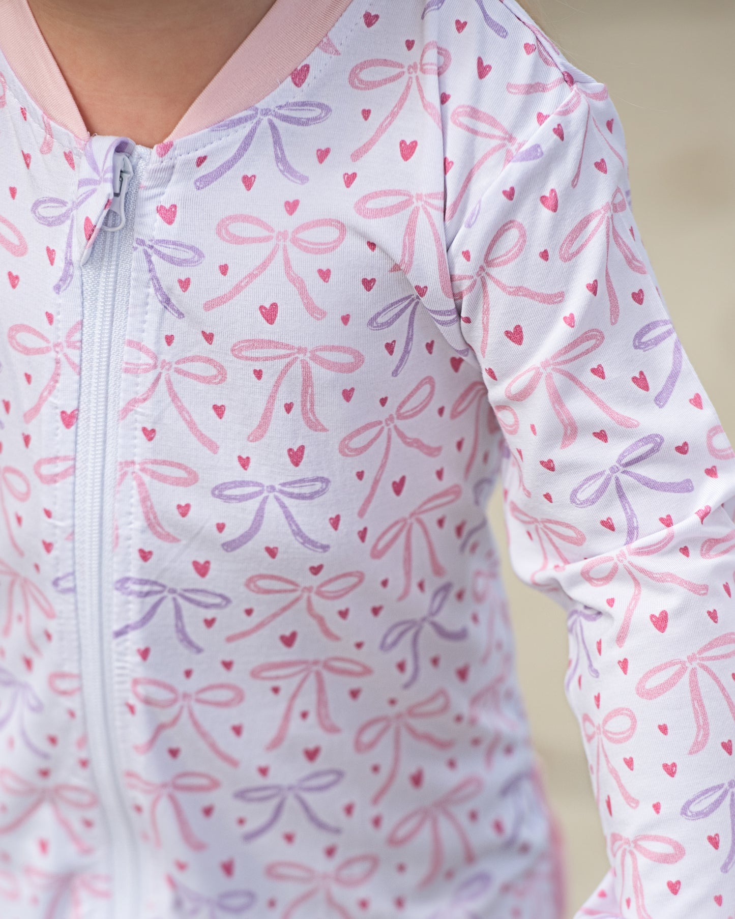 Close-up of a baby onesie with pink and purple bow pattern on a light background