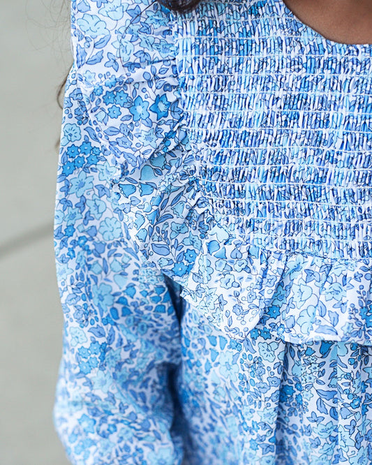 Close-up of a blue floral dress with smocked waist on a neutral background