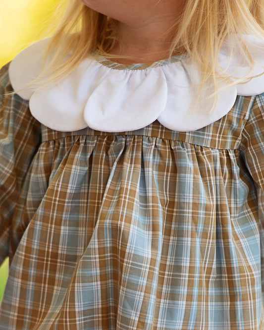 Close-up of a child's dress with a white ruffled collar and plaid pattern.