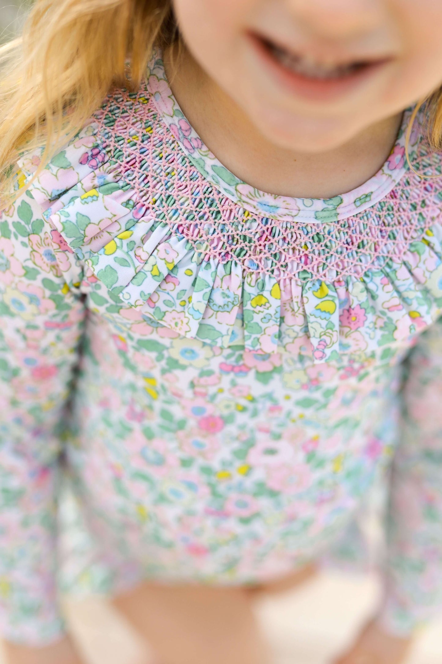 Close-up of a child wearing a floral rashguard with smocked details.