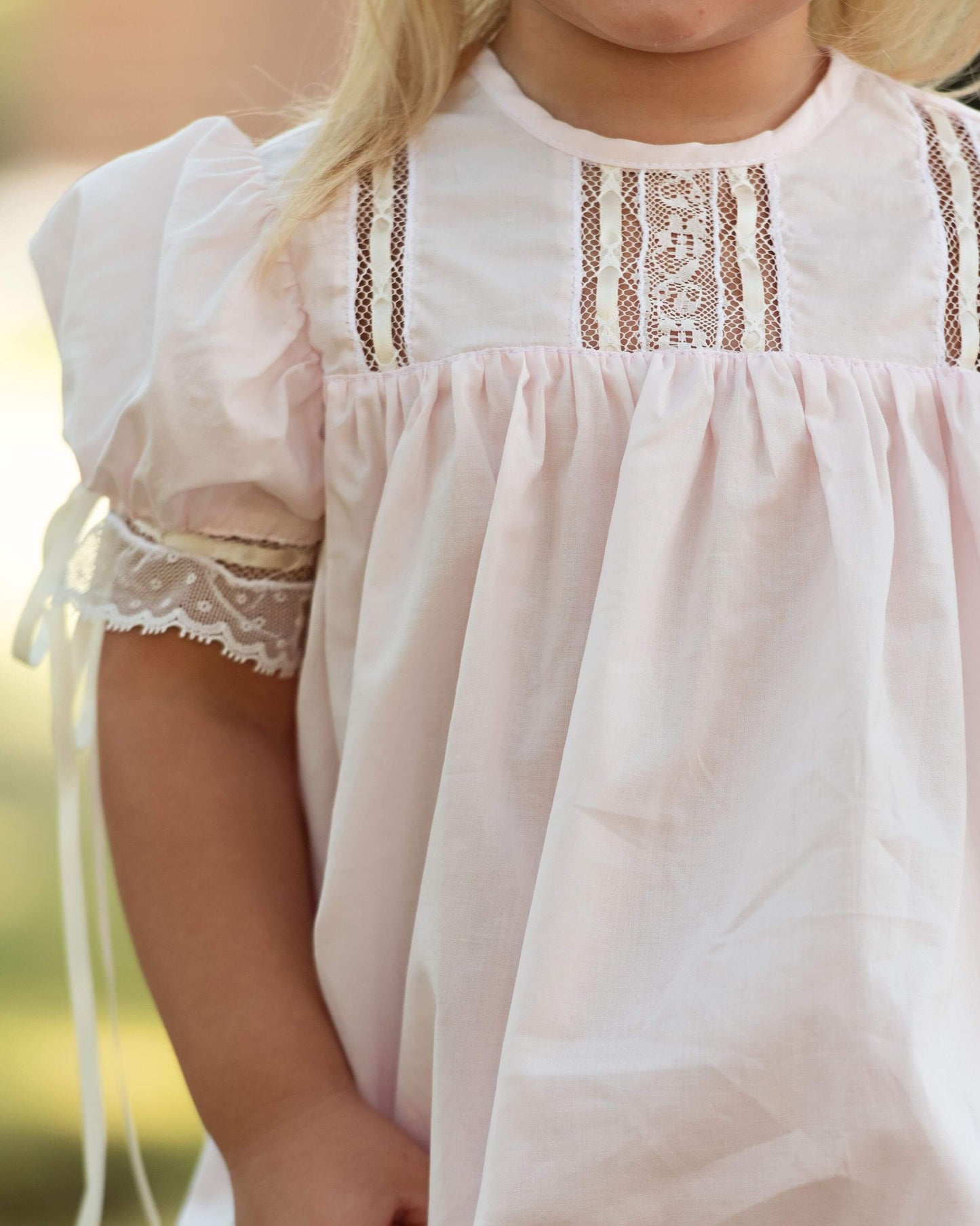 Close-up of a child wearing a white dress with lace details.