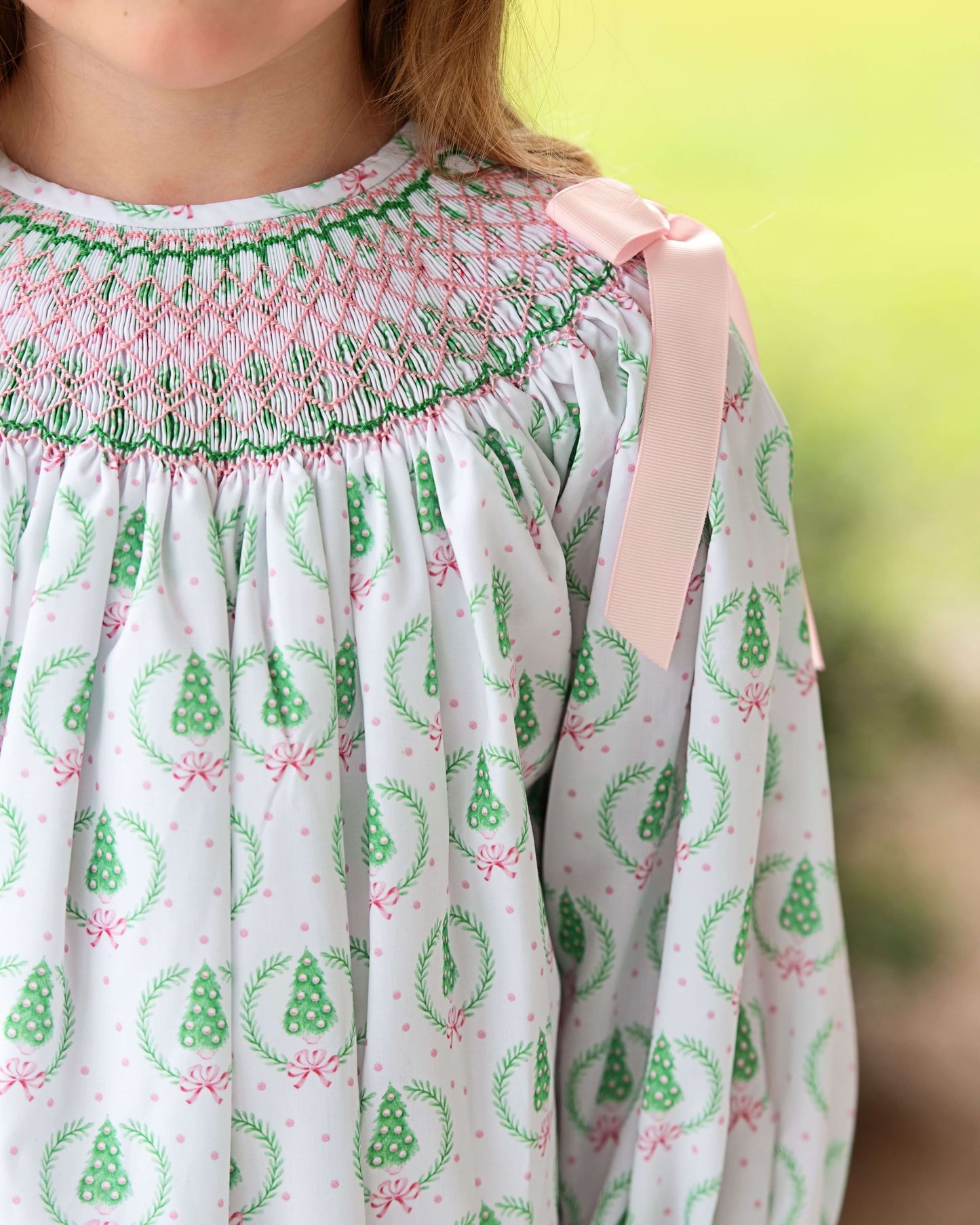 Close-up of a dress with green and pink patterns against a blurred natural background