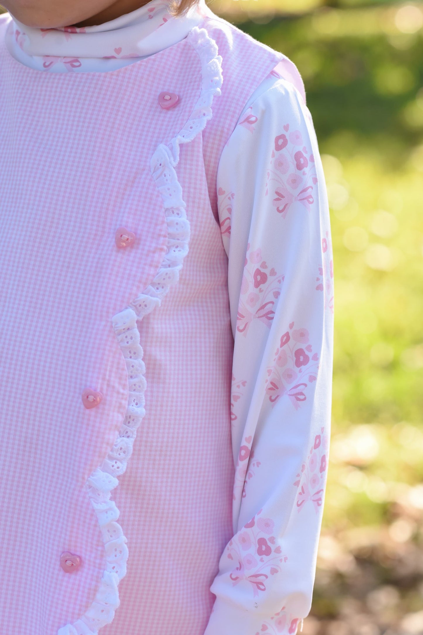 Close-up of a pink dress with floral patterns and ruffled details.