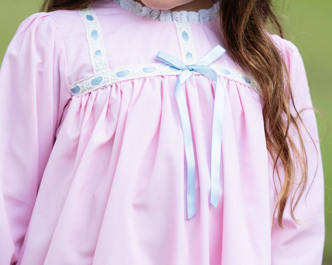 Close-up of a pink nightgown with blue accents on a blurred green background